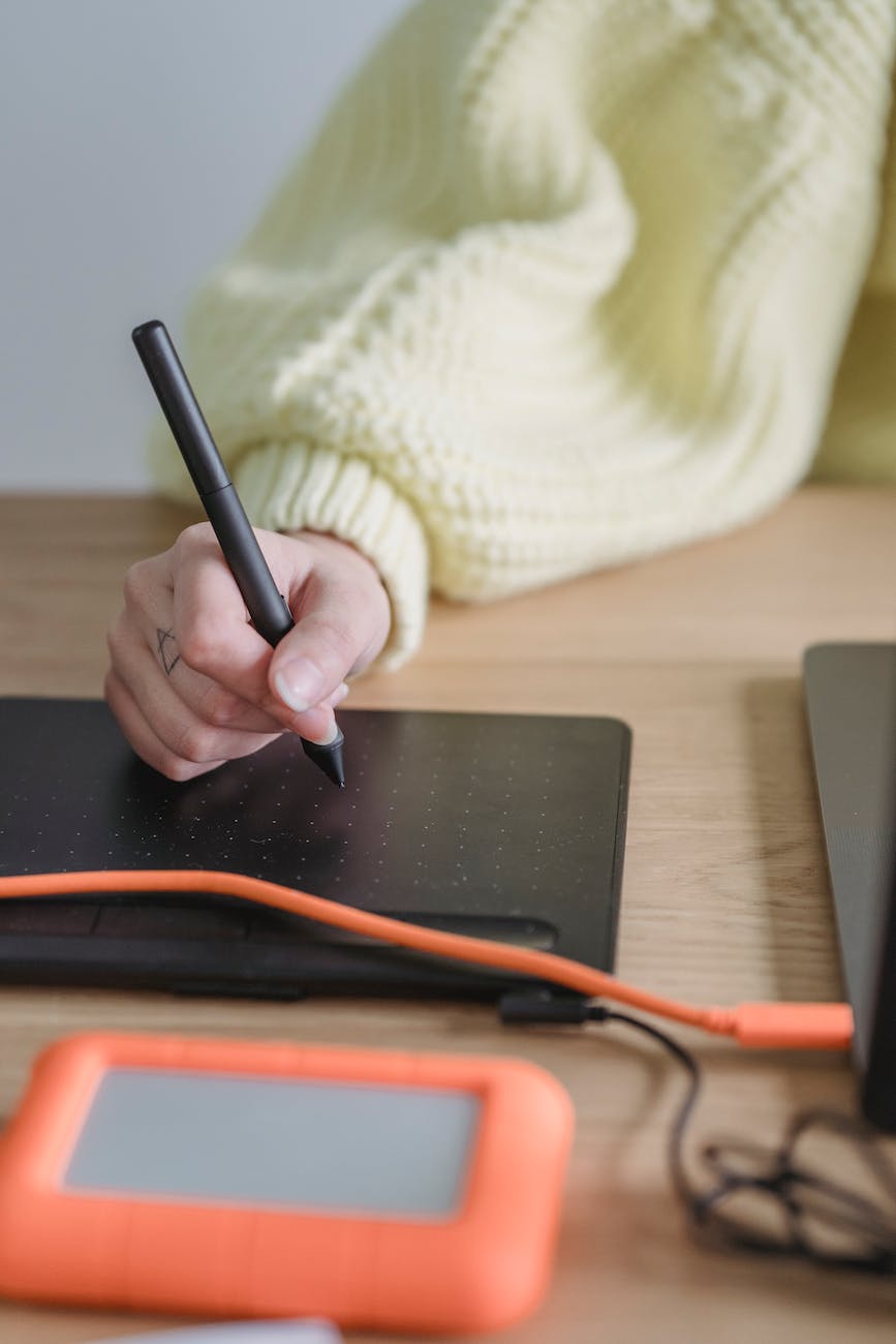 anonymous woman writing on graphic tablet external hard drive